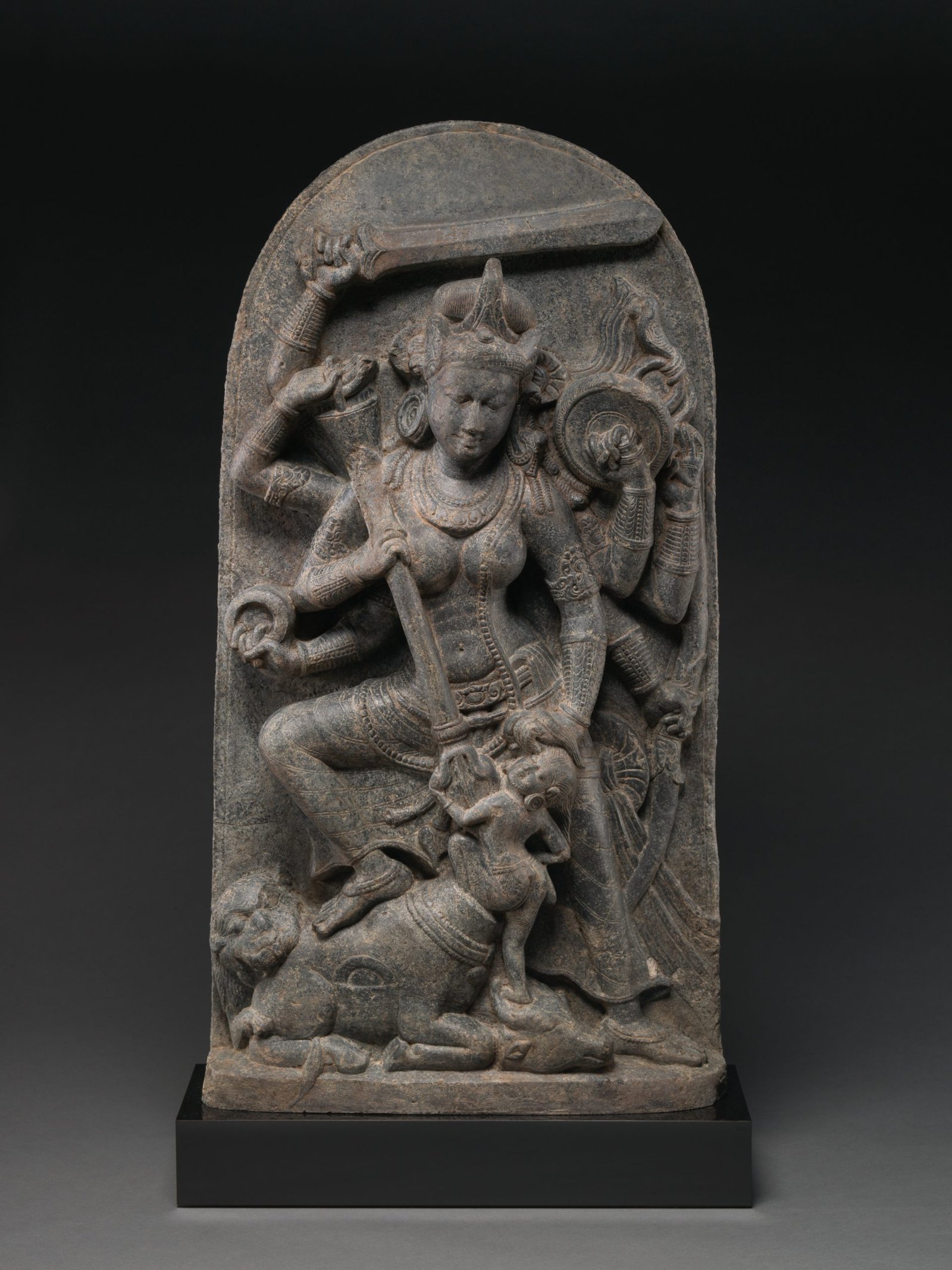 Multi-armed Durga carrying divine weapons while defeating Mahisha.