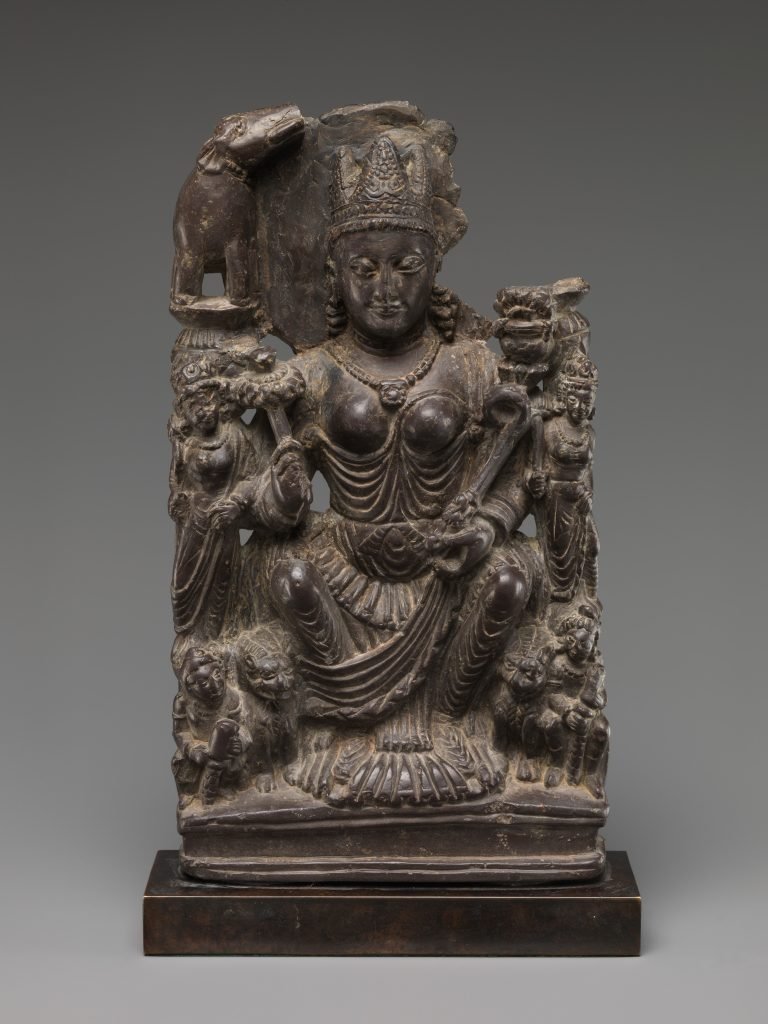 Stone sculpture of Gaja Lakshmi beneath an elephant, with smaller figures beside her.