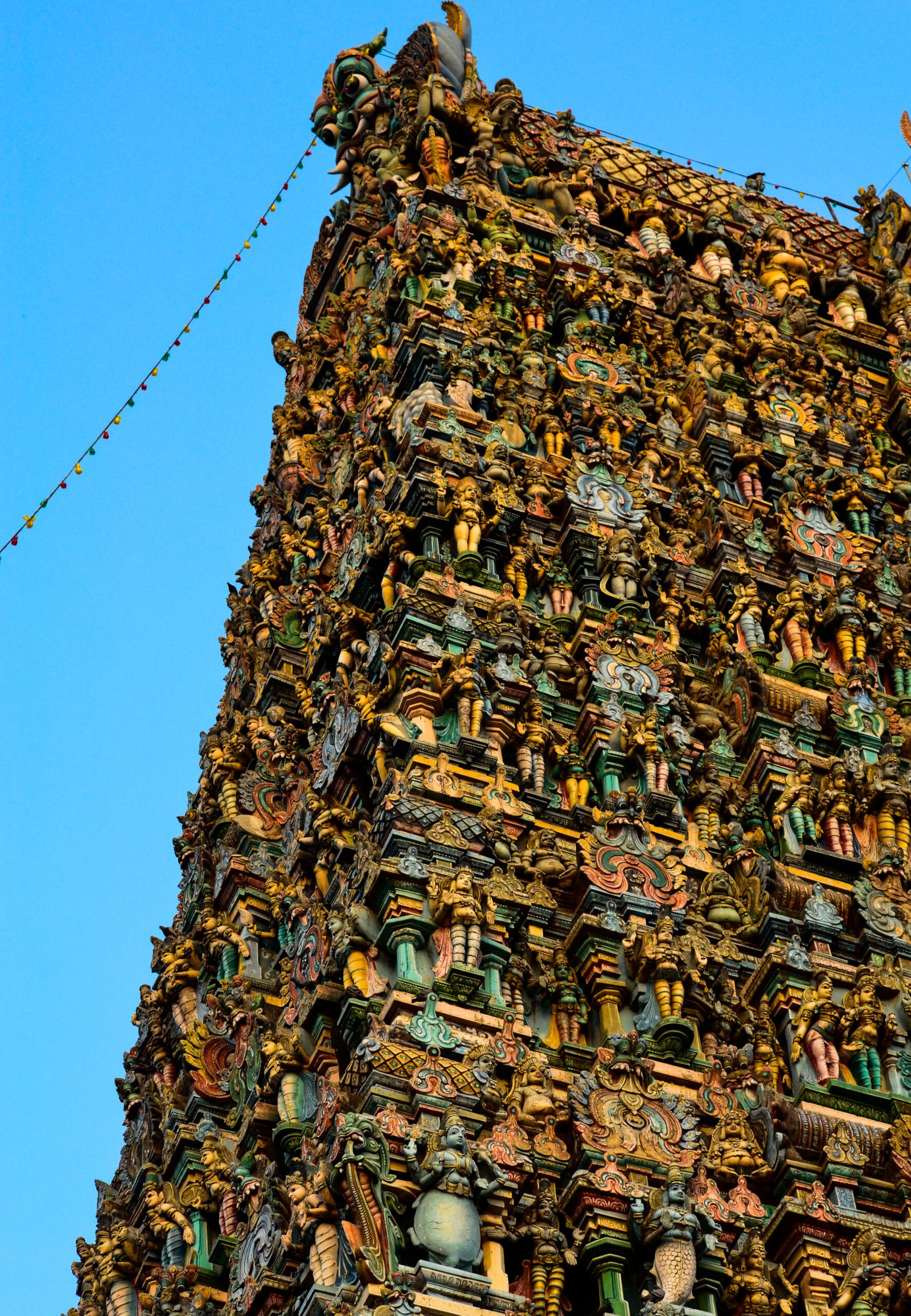 Side of the west gopuram at Meenakshi Temple, its tiers covered with brightly painted sculpted figures.