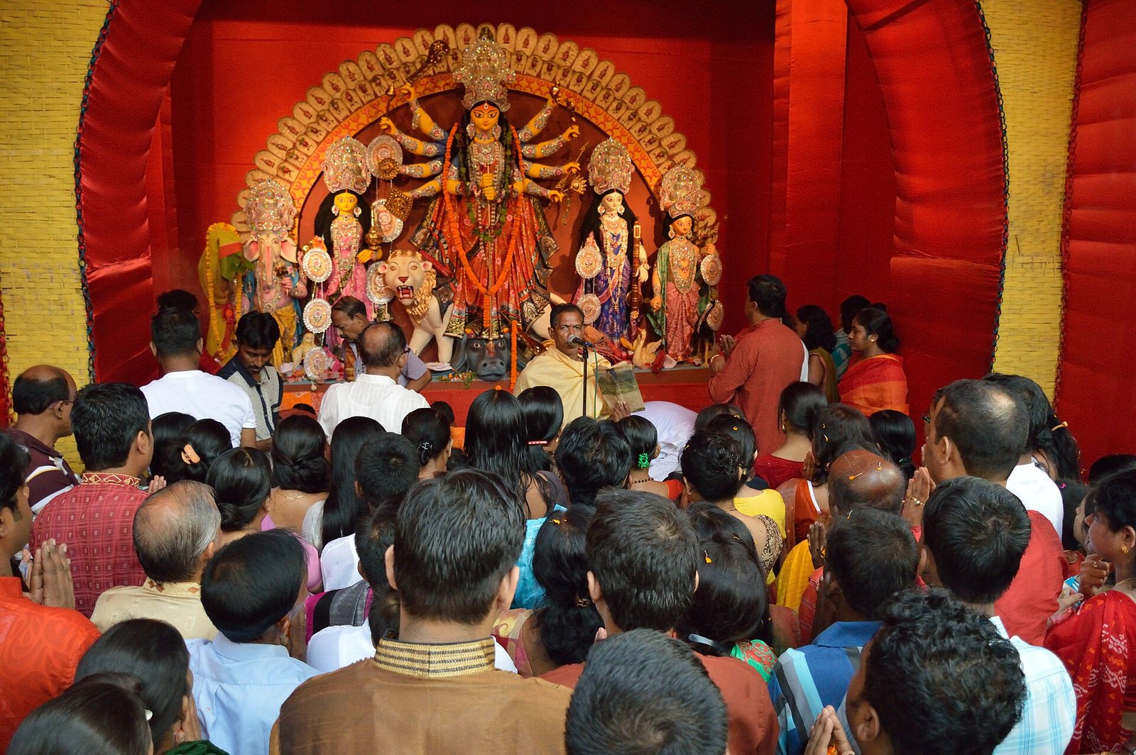 Worshippers gather with folded hands before the Durga tableau as a priest leads pushpanjali at Biswamilani Club in Howrah.