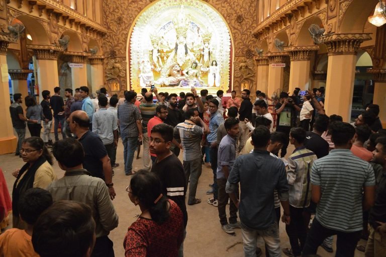 Visitors gather before the illuminated Durga tableau beneath ornate arches inside the Maddox Square Durga Puja pandal in Kolkata.