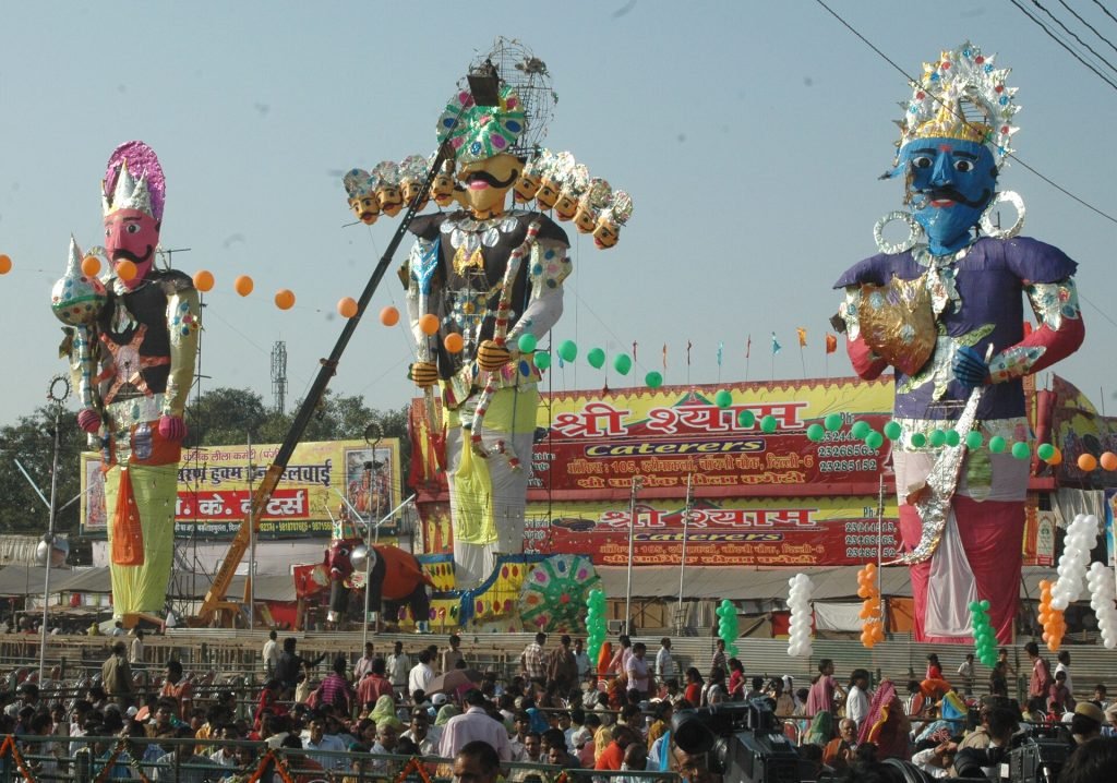 Three towering, brightly decorated effigies stand above spectators at Subhash Maidan in Delhi, with the ten-headed Ravana in the center.