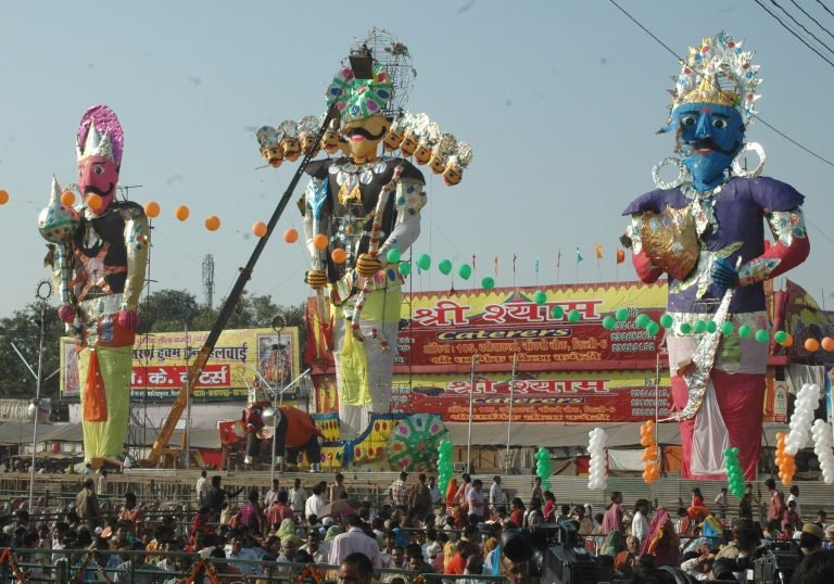 Three towering, brightly decorated effigies stand above spectators at Subhash Maidan in Delhi, with the ten-headed Ravana in the center.