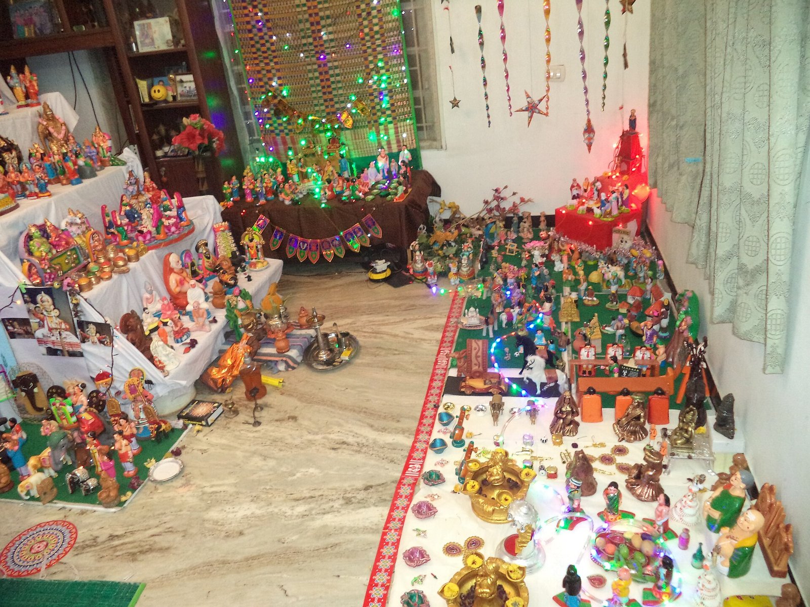 A household Golu display in Tamil Nadu fills tiered shelves and floor arrangements with dolls, sacred figures, miniature scenes and strings of colored lights.
