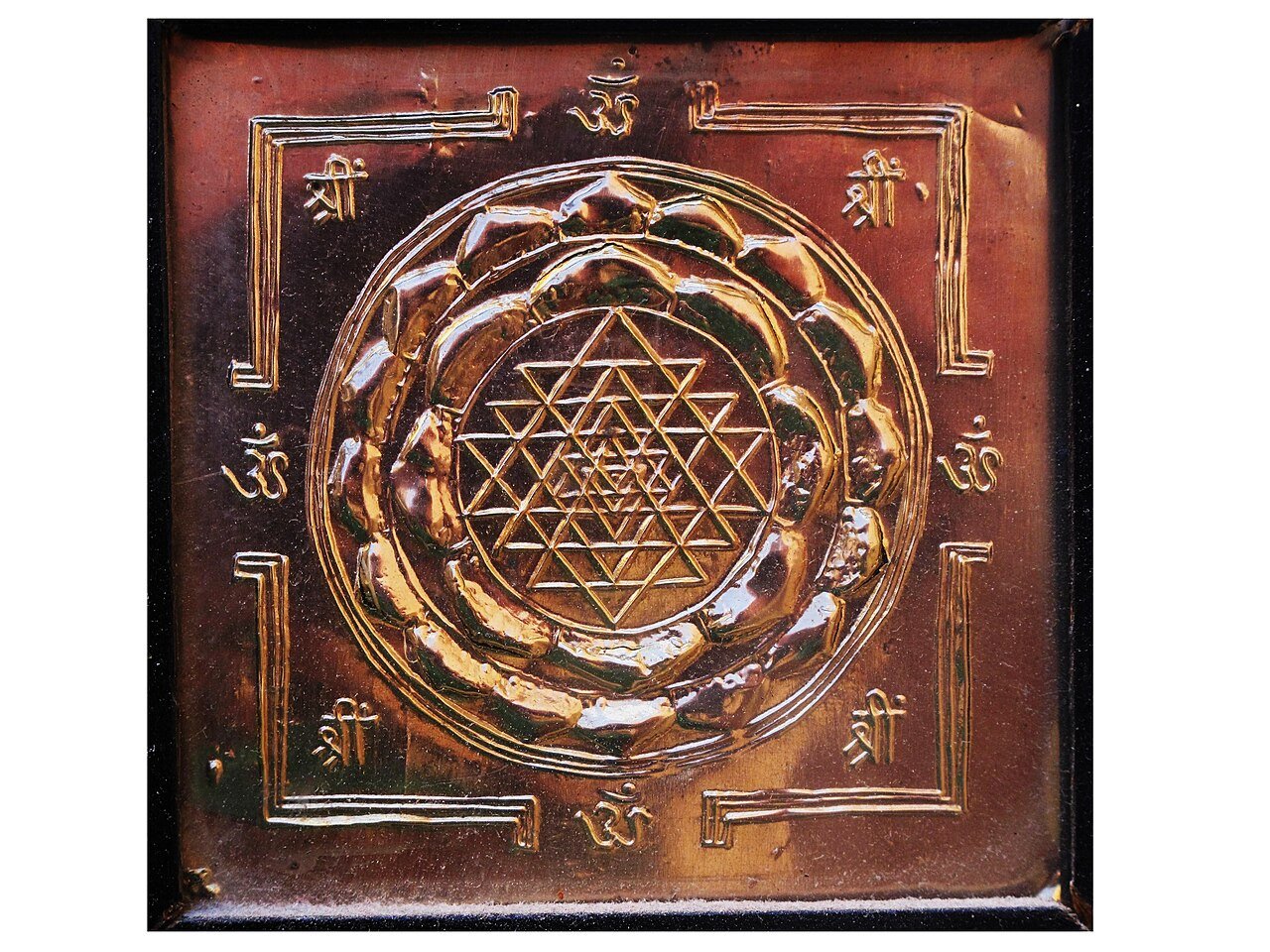 Copper Sri Chakra plaque with interlocking upward- and downward-pointing triangles, central point, surrounding lotus rings and four gateways within a square frame.