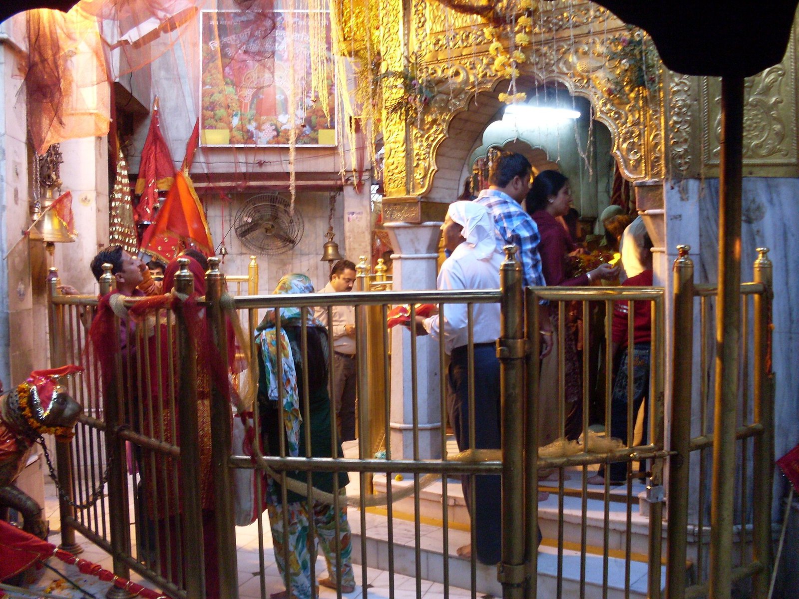 Visitors stand behind brass railings at the gold-colored decorated shrine entrance in Chintpurni temple.