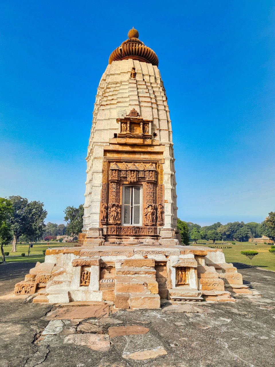 Parvati Temple at Khajuraho, with a carved stone doorway, tall pale tower and stepped plinth against a blue sky.